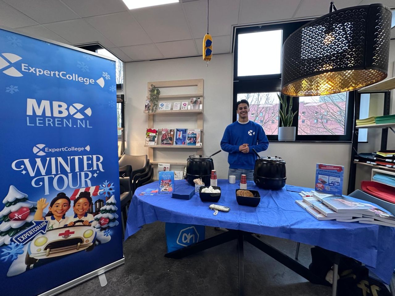 ExpertCollege-collega achter de Winter Tour-stand met warme chocolademelk
